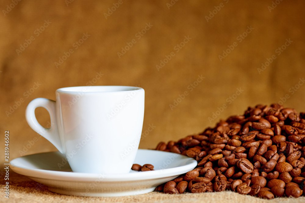 White cup and coffee beans on a blurred background. White cup and coffee beans on a blurred background.