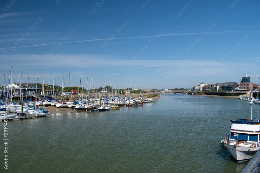 River Arun Littlehampton looking north at low tide towards the recently opened Harbour Lights Cafe, yachts are moored on the west bank at the Yacht Club on a beautiful sunny July day in England.