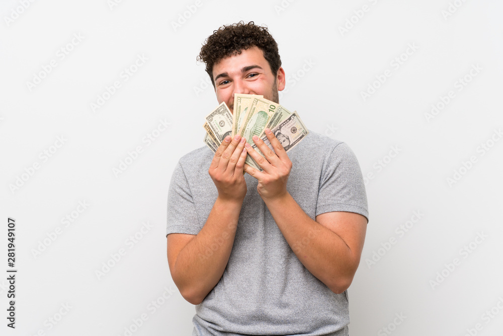 Man with curly hair over isolated wall taking a lot of money Man with curly hair over isolated wall taking a lot of money