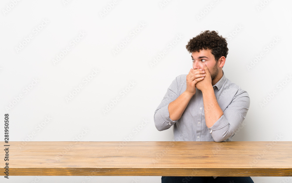 Young man with a table covering mouth and looking to the side Young man with a table covering mouth and looking to the side