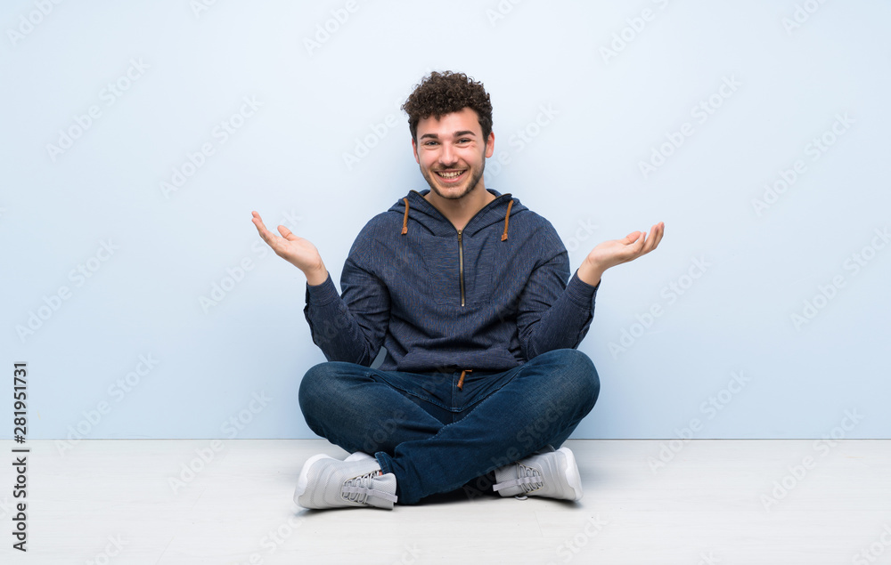 Young man sitting on the floor with shocked facial expression