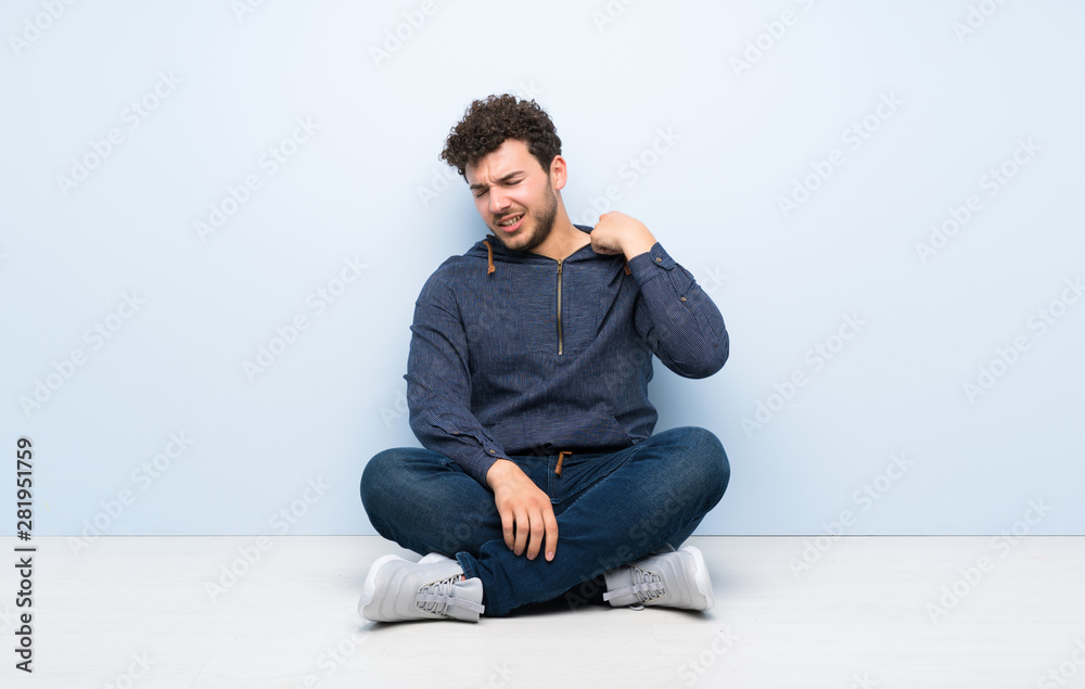 Young man sitting on the floor with tired and sick expression Young man sitting on the floor with tired and sick expression