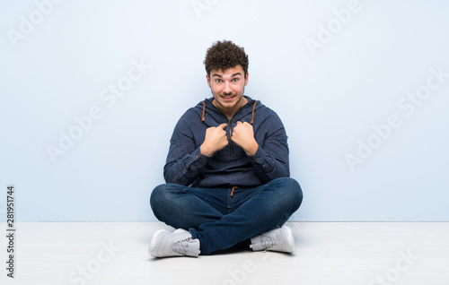 Young man sitting on the floor with surprise facial expression © luismolinero