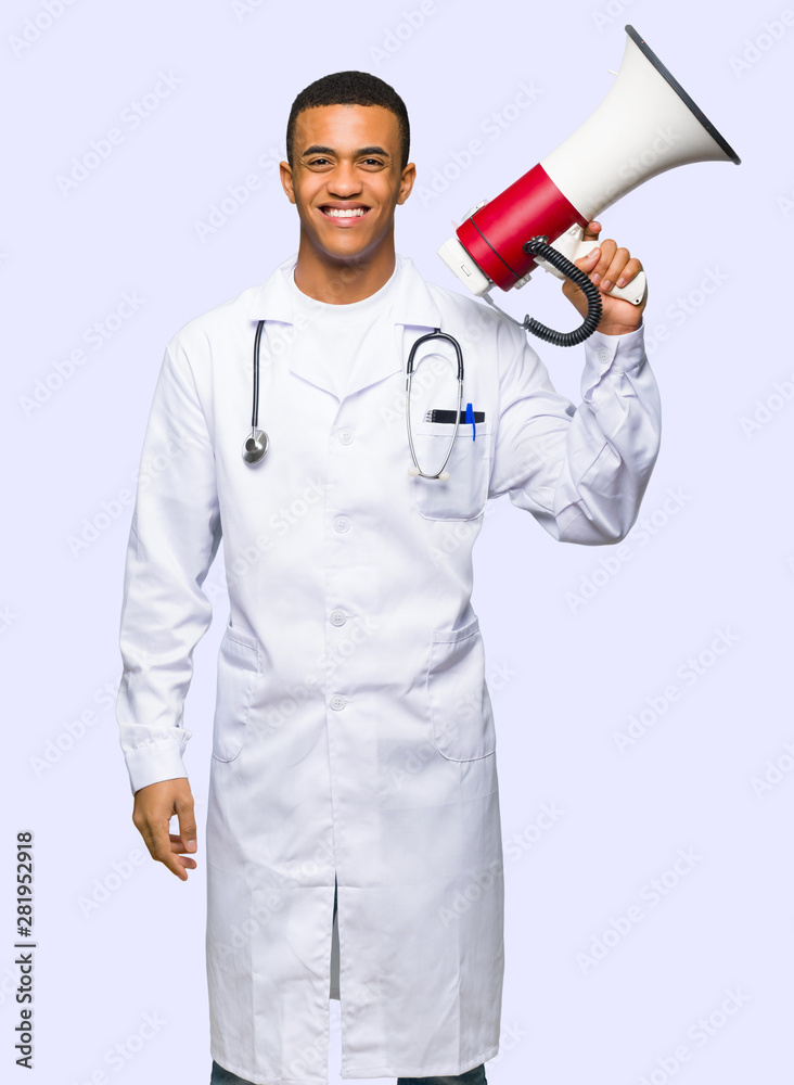 Fototapeta premium Young afro american man doctor holding a megaphone on isolated background