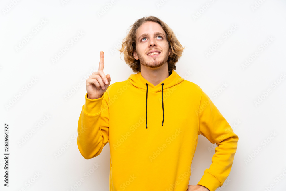 Blonde man with sweatshirt over white wall showing and lifting a finger in sign of the best Blonde man with sweatshirt over white wall showing and lifting a finger in sign of the best