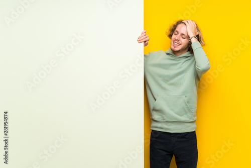 Blonde man holding a big empty placard laughing