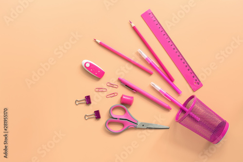 Flat lay pink stationery on a pastel background. Top view, copy space. Glass, scissors, pencil, pen, ruler, eraser and paper clip.