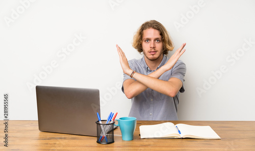 Blonde man with a laptop making NO gesture