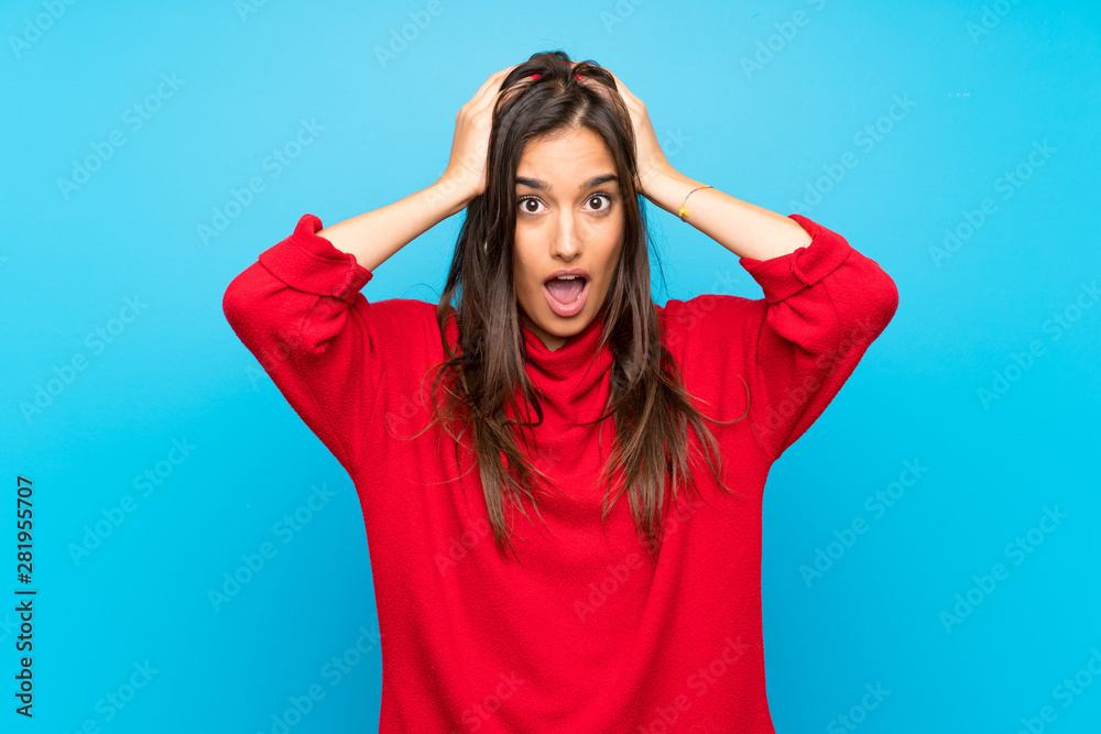 Young woman with red sweater over isolated blue background with surprise facial expression Young woman with red sweater over isolated blue background with surprise facial expression