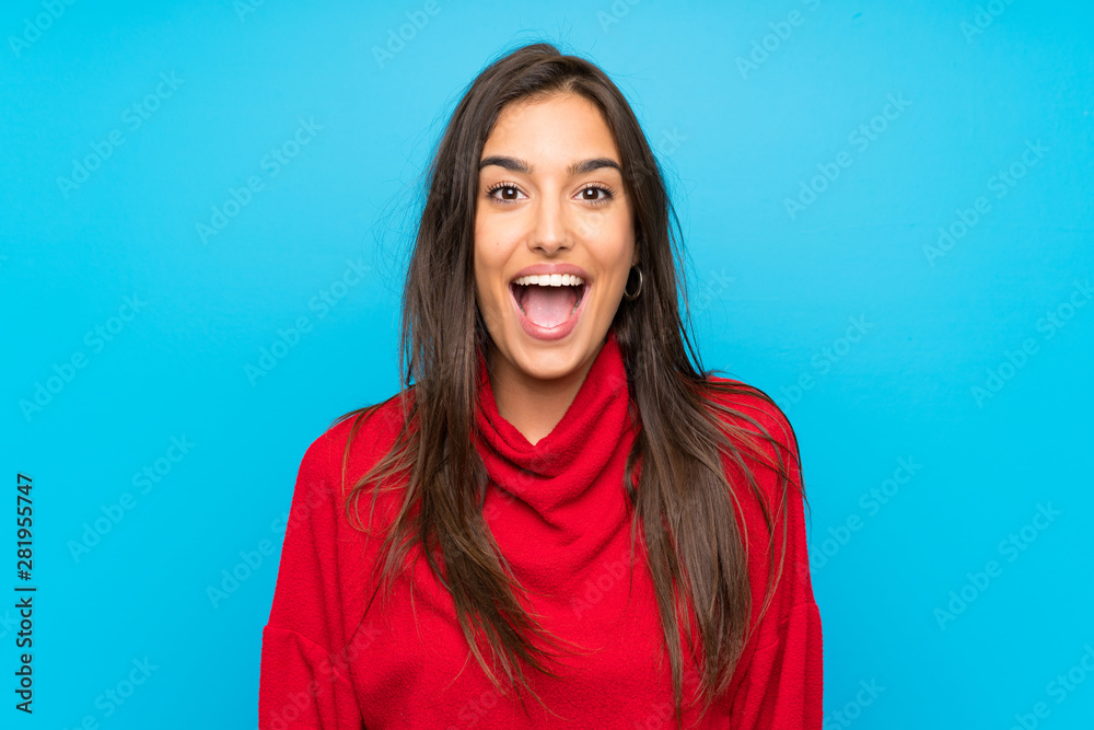 Young woman with red sweater over isolated blue background with surprise facial expression Young woman with red sweater over isolated blue background with surprise facial expression