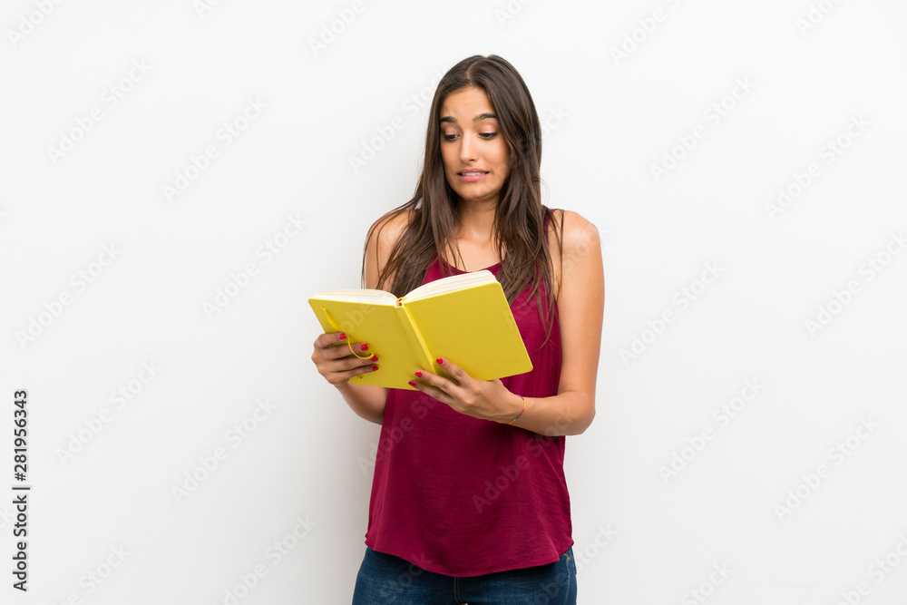 Young woman over isolated white background holding and reading a book Young woman over isolated white background holding and reading a book