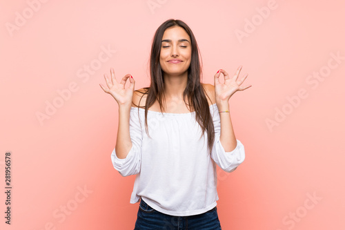 Young woman over isolated pink background in zen pose