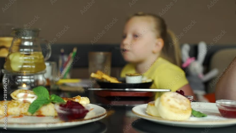 Close Up of Woman Drinking Herbal Tea in a Coffe Shop while her Little Daughter Drinking Chocolate Shake from Straw. Selective Focus on Cup of Tea. Foods and Drink Concept Close Up of Woman Drinking Herbal Tea in a Coffe Shop while her Little Daughter Drinking Chocolate Shake from Straw. Selective Focus on Cup of Tea. Foods and Drink Concept