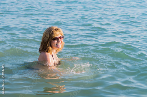 A beautiful elderly woman enjoying retirement bathing in the sea. A happy woman laughing during a holiday trip
