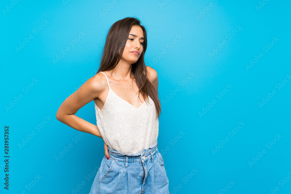 Young woman over isolated blue background suffering from backache for having made an effort
