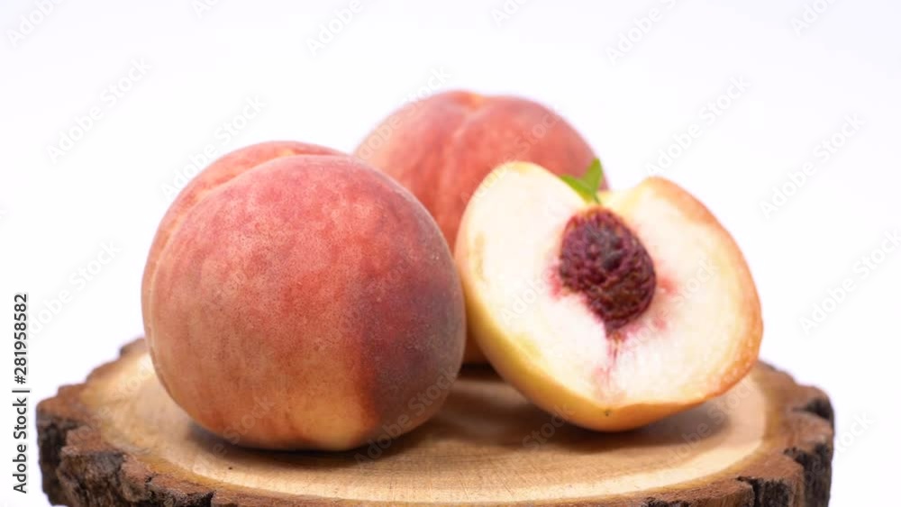 Ripe white peaches rotate around its axis. Peaches on a white background. White peach on a wooden saw Ripe white peaches rotate around its axis. Peaches on a white background. White peach on a wooden saw