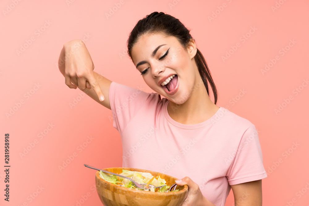 Happy Teenager girl over isolated pink wall with salad Happy Teenager girl over isolated pink wall with salad
