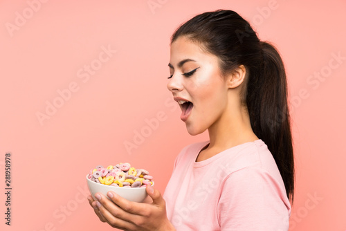 Teenager girl having breakfast cereals over isolated pink wall