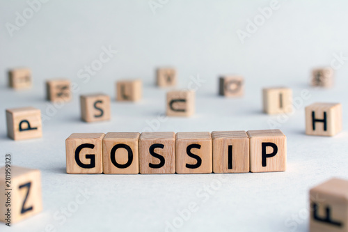 Gossip - word from wooden blocks with letters, other people’s private lives concept, random letters around, top view on wooden background