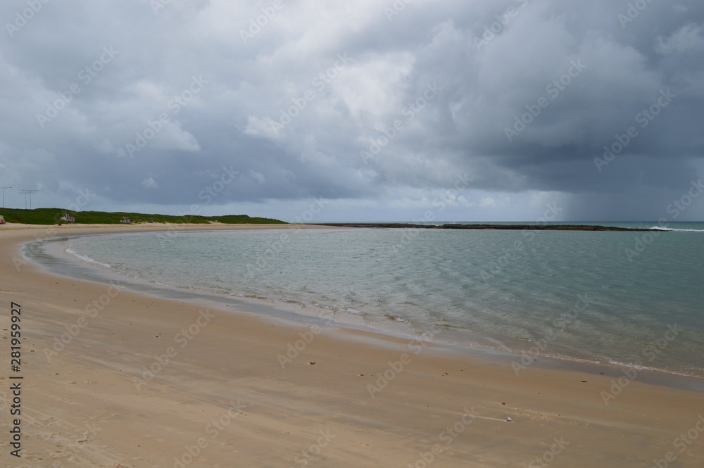 Deserted beach with calm waves under a cloudy sky