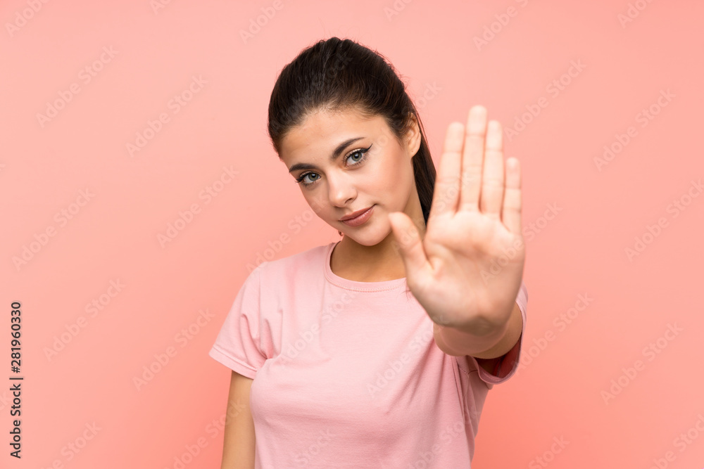 Teenager girl over isolated pink background making stop gesture with her hand Teenager girl over isolated pink background making stop gesture with her hand