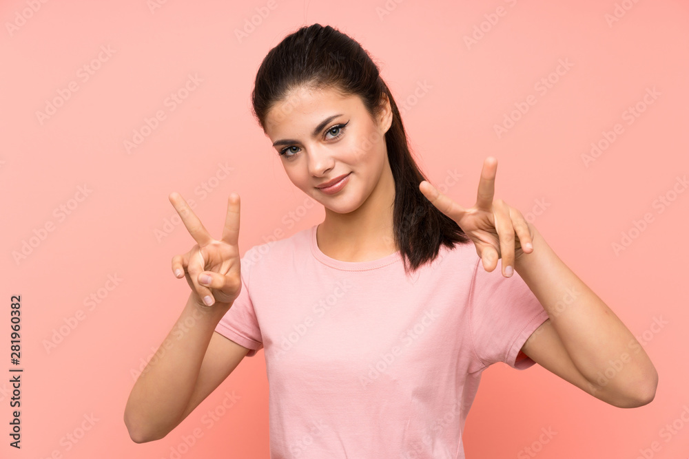 Teenager girl over isolated pink background smiling and showing victory sign Teenager girl over isolated pink background smiling and showing victory sign