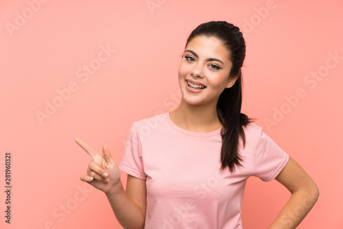 Teenager girl over isolated pink background pointing finger to the side