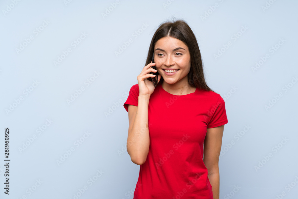 Brunette young woman with a mobile phone over isolated blue wall Brunette young woman with a mobile phone over isolated blue wall