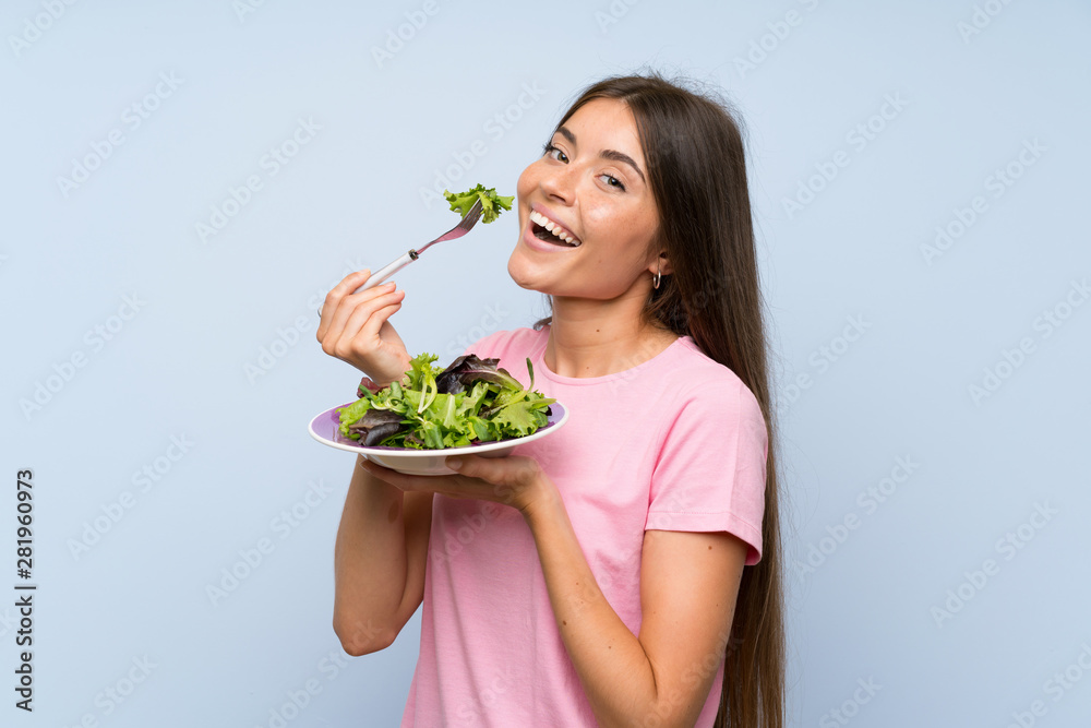 Young woman with salad over isolated blue background Young woman with salad over isolated blue background