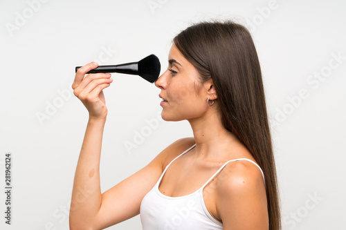 Pretty young woman with makeup brush over isolated grey background