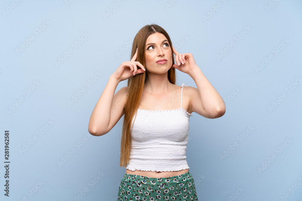 Fototapeta premium Young woman over isolated blue background having doubts and thinking