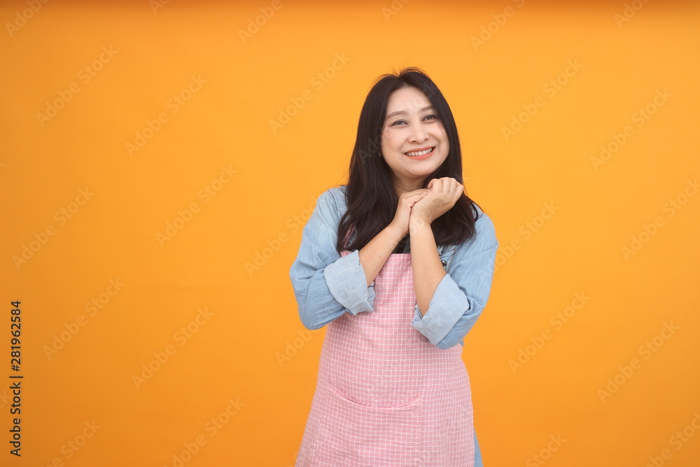 Happy Asian woman is cooking with apron for cooking advertise theme on on yellow background. Happy Asian woman is cooking with apron for cooking advertise theme on on yellow background.