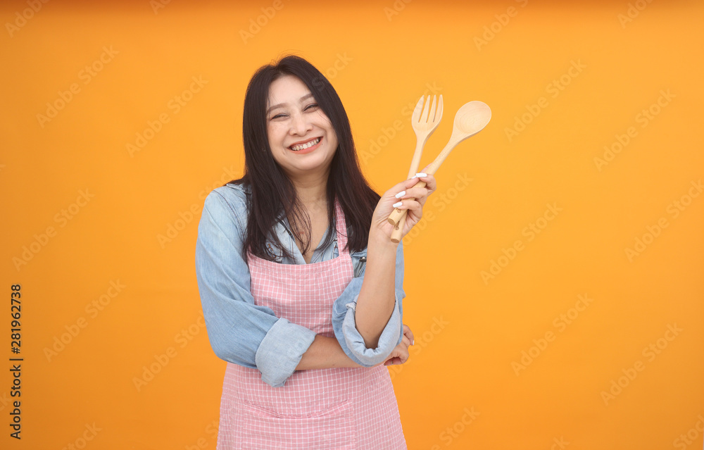 Happy Asian woman is cooking with apron for cooking advertise theme on on yellow background. Happy Asian woman is cooking with apron for cooking advertise theme on on yellow background.