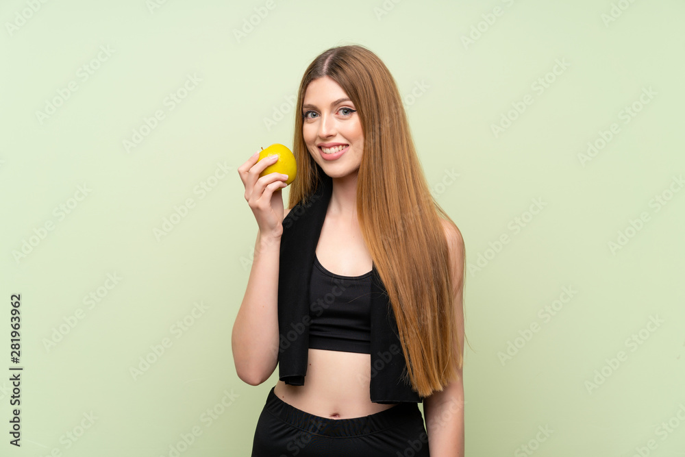 Young sport woman over isolated green background with an apple Young sport woman over isolated green background with an apple