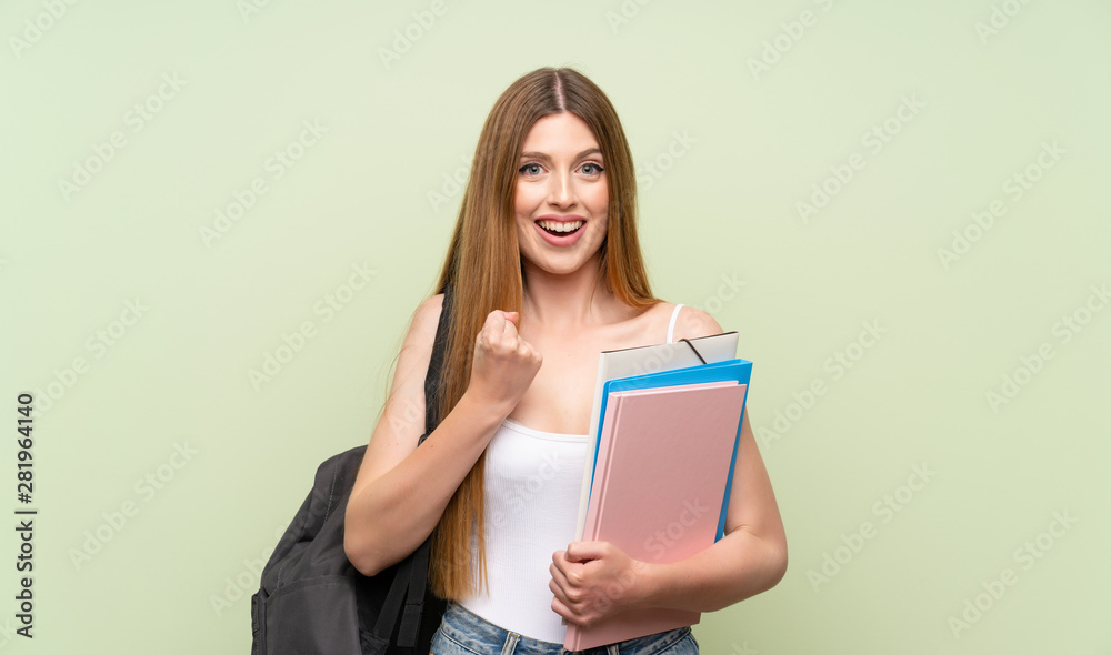Young student woman over isolated green background celebrating a victory Young student woman over isolated green background celebrating a victory