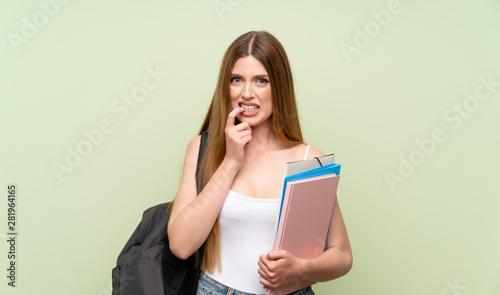Young student woman over isolated green background nervous and scared