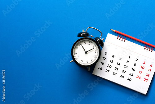 close up of calendar, alarm clock, pencil on the blue table background, planning for business meeting or travel planning concept