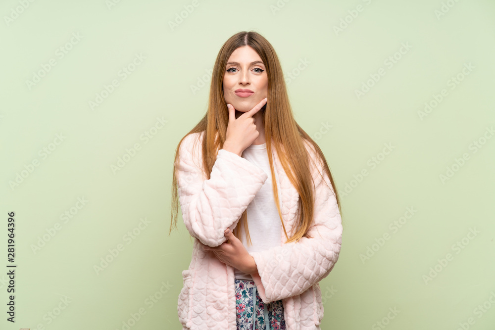 Young woman in dressing gown over green wall laughing Young woman in dressing gown over green wall laughing