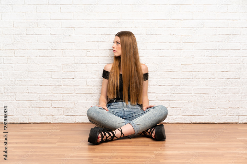Young woman sitting on the floor looking side Young woman sitting on the floor looking side