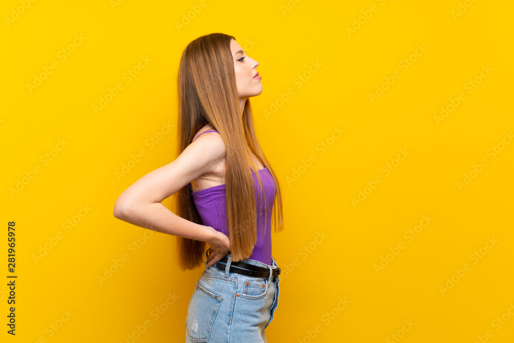 Young woman over isolated yellow background suffering from backache for having made an effort Young woman over isolated yellow background suffering from backache for having made an effort