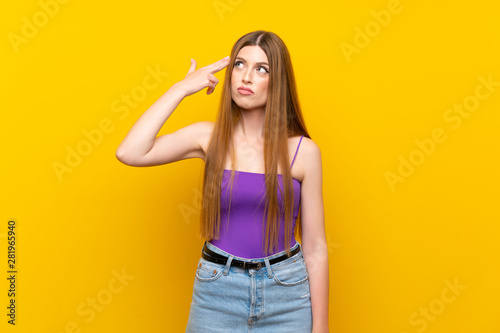 Young woman over isolated yellow background with problems making suicide gesture