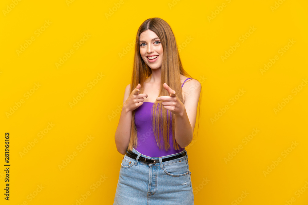 Young woman over isolated yellow background pointing to the front and smiling Young woman over isolated yellow background pointing to the front and smiling