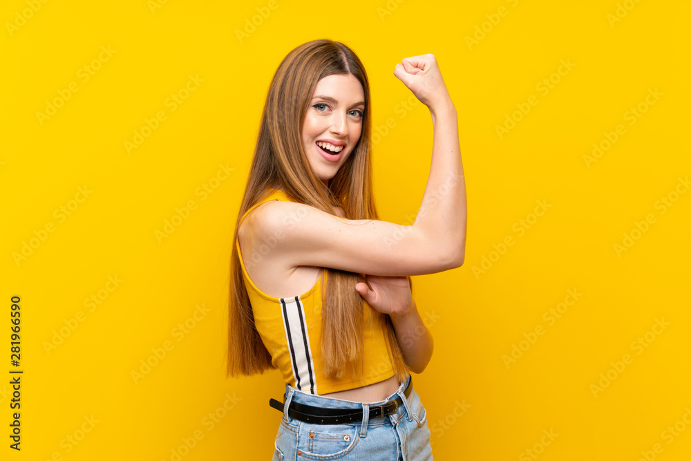 Young woman over isolated yellow background making strong gesture Young woman over isolated yellow background making strong gesture