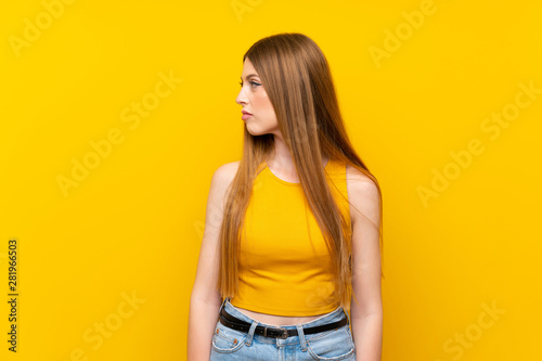 Young woman over isolated yellow background looking side