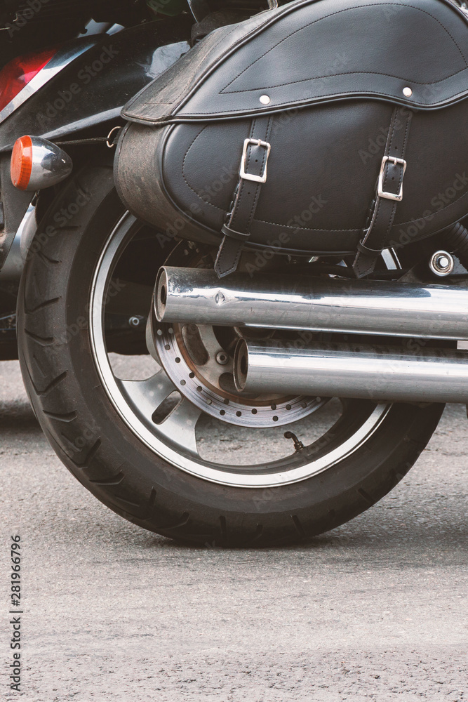 rear part of a motorcycle: wheel, exhaust pipe and black leather