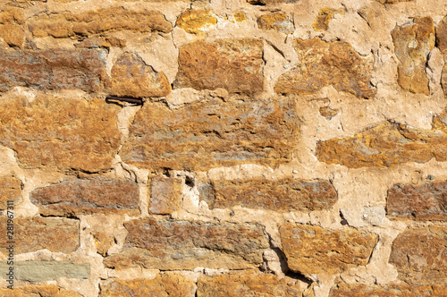 Schöne helle Sandsteinmauer von einem alten Bauernhof ohne Bewuchs mit vielen unterschiedlich großen Fugen und verschieden großen Steinen und teilweise mit Zement ausgebessert
