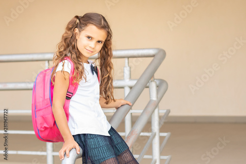 first day of school. Girl schoolgirl goes to first grade. Girl sitting near the school and waiting for a lesson