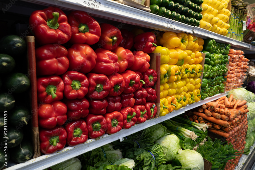 Bell peppers, greens, carrots, cucumbers, lettuce, vegetables in produce section of grocery store