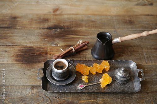 turkish coffee in cups with vintage pattern with cezve and sweet caramel sugar on a wooden rustic table with copy space for text or image. Still life. Gastronomic Travel.