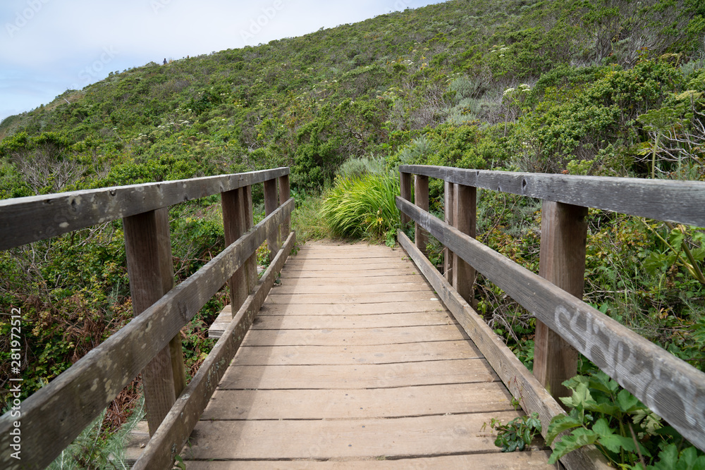 View of walking across narrow wooden bridge in the wilderness